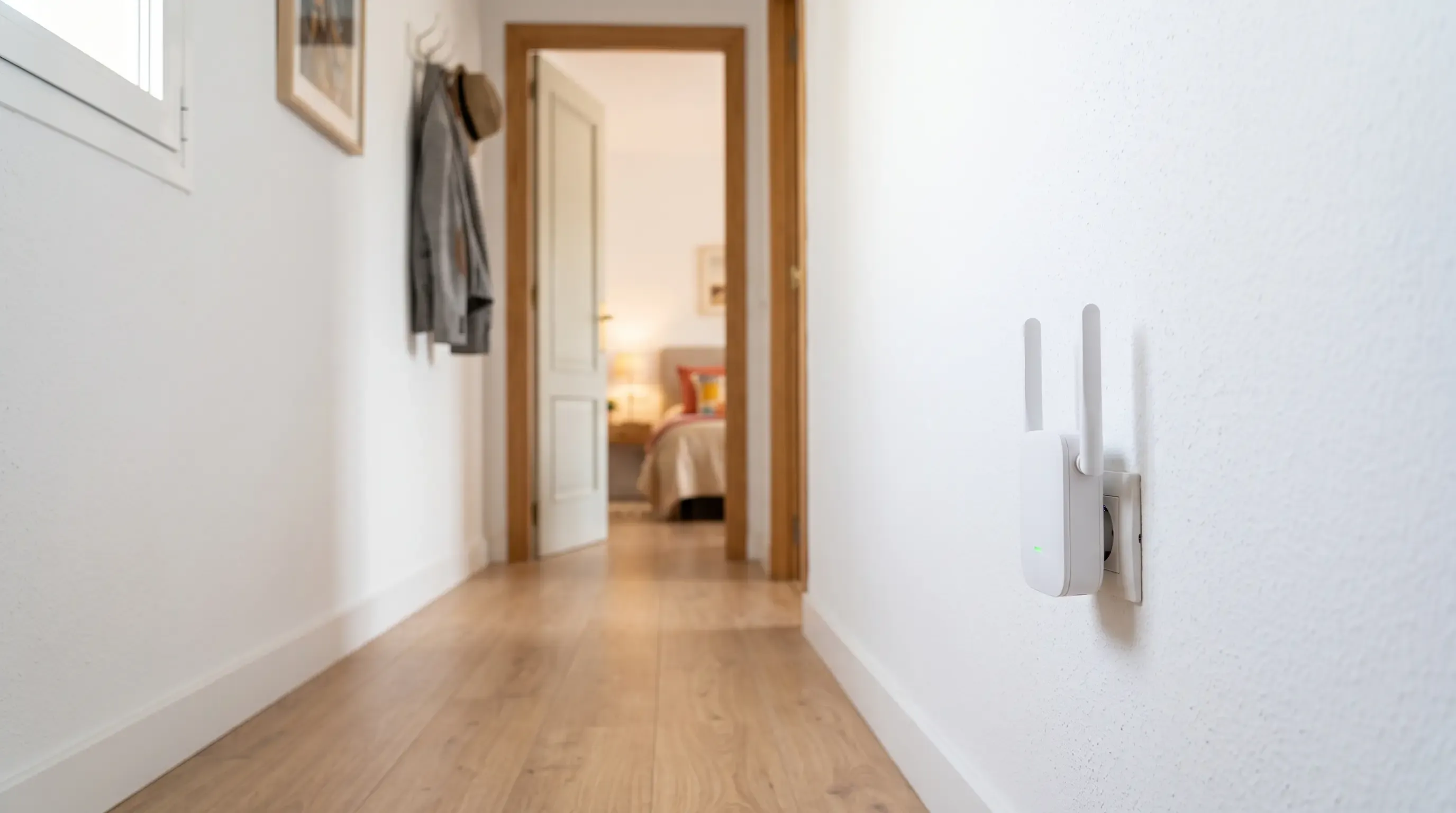 Repetidor WiFi conectado a una toma de corriente en un pasillo, a mitad de camino entre el router y la habitación sin cobertura